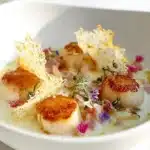 Saint-Jacques poêlées avec fenouil et crème au gruyère sur une assiette